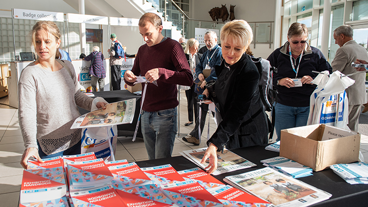 Photo of CRE foyer with people collecting the exhibition handbook